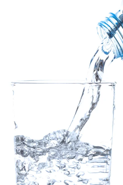 Pouring drinking water from bottle into glass on white background. — Stock Photo, Image