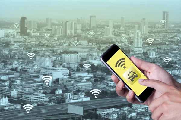 Smartphone telefon taksiyle uygulama smartphone ve cityscape arka plan ile ağ wifi kullanarak adamın elini.