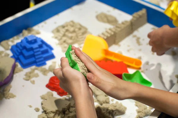 Kids playing plastic mold toys with sand on sandbox. Background