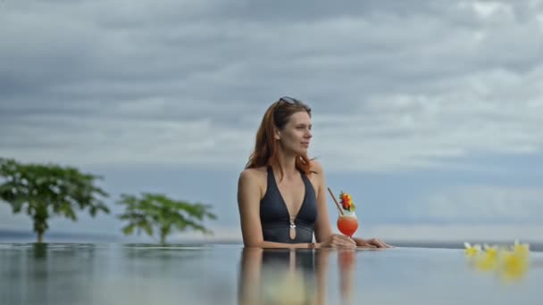 Retrato de una hermosa mujer sosteniendo cóctel exótico está en la piscina en la isla de Bali . — Vídeos de Stock