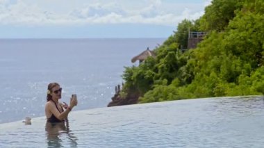 Mutlu Amerikalı kadın spa havuzunda akıllı telefon kullanarak sohbet ediyor..