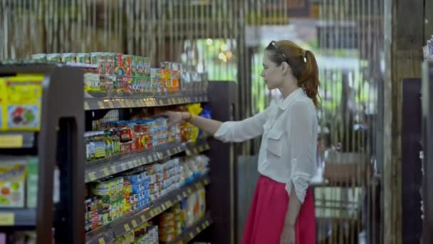 Bali, Indonesia - Marzo 2019: La joven americana elige comida de pie cerca de los estantes en el supermercado . — Vídeo de stock