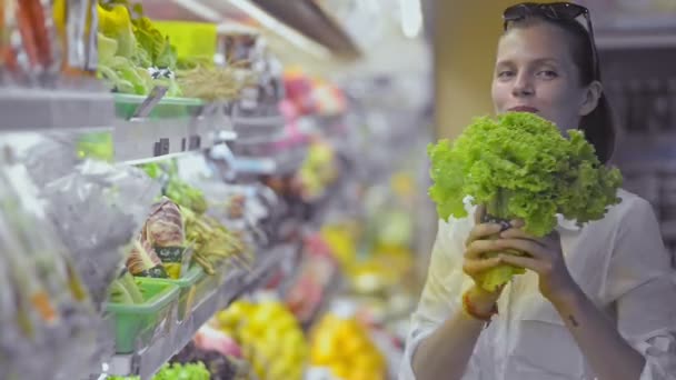 Happy american woman dancing with green salad in hand standing in supermarket. — Stock Video