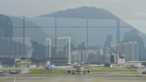 Hong Kong, Çin - Ağustos 2019: Pencereden şehrin güzel manzarası ve havaalanında yürüyen insanların yansımaları. — Stok video