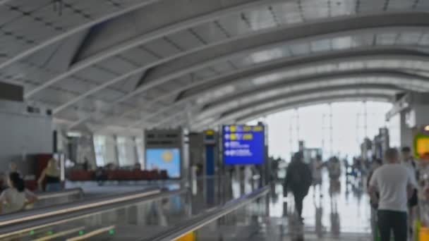 Terminal desenfocada irreconocible del aeropuerto. pasajeros ambulantes con maletas de equipaje. tablero de puerta — Vídeo de stock