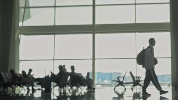 Silhouttes irreconocibles de personas con equipaje caminando en la sala de espera del aeropuerto. plano desenfocado borroso — Vídeos de Stock