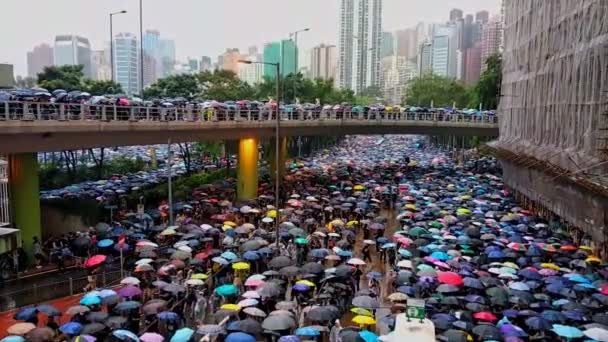 Hong Kong, Chiny - sierpień 2019: Osoby z parasolami spacerujące ulicą Hongkong podczas demonstracji w deszczowe dni. — Wideo stockowe