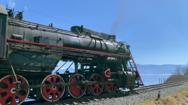 Lago Baikal, Rusia - Agosto de 2019: Vieja locomotora con vapor se encuentra en la carretera ferroviaria en un hermoso campo natural. — Vídeos de Stock