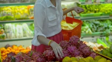 Egzotik meyveler alan genç bir kadın süpermarkette seyahat ederken alışveriş yapıyor..