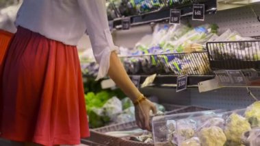 Kadın markette taze sebze seçiyor. konsept alışveriş, plastik, organik