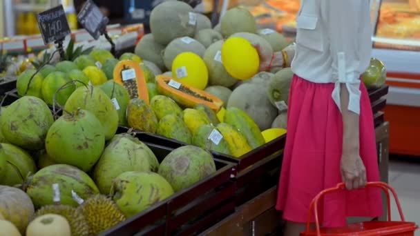 Joven americana mujer elegir exótico frutas de pie en supermercado durante asiático viajar . — Vídeos de Stock