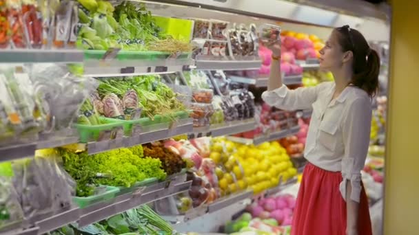 Νεαρή Αμερικανίδα κοκκινομάλλα γυναίκα διαλέγει ντοματίνια που έχουν χρόνο για ψώνια στο κατάστημα βιολογικών προϊόντων. — Αρχείο Βίντεο