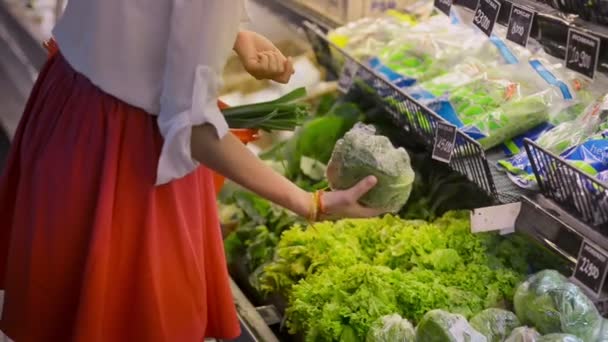 Mujer joven eligiendo verduras y verduras de pie en el supermercado durante el viaje asiático . — Vídeo de stock