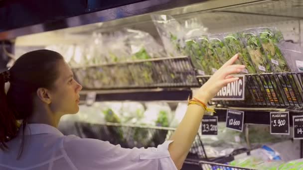 Молода біла руда волохата жінка вибирає свіжу зелень, що стоїть в органічному магазині під час азіатських подорожей . — стокове відео