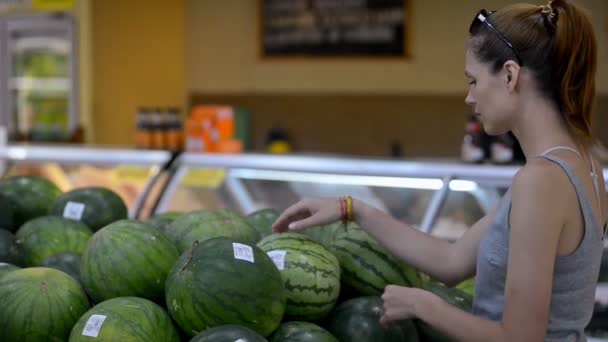 Vrouw kloppen kiezen biologische watermeloen in supermarkt. klant die fruit selecteert — Stockvideo