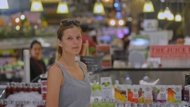 Молодая американская модель женщина позирует в супермаркете. женщина смотрит в камеру с улыбкой — стоковое видео