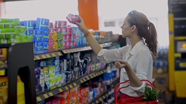 Bali, Indonesia - March, 2019: Ung amerikansk rödhårig kvinna väljer feminina produkter under shoppingtiden i moderna snabbköp. — Stockvideo