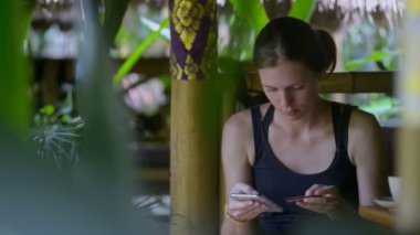 Amerikalı genç bir kadın Asya seyahati sırasında akıllı telefon ve kartla online alışveriş yapıyor..