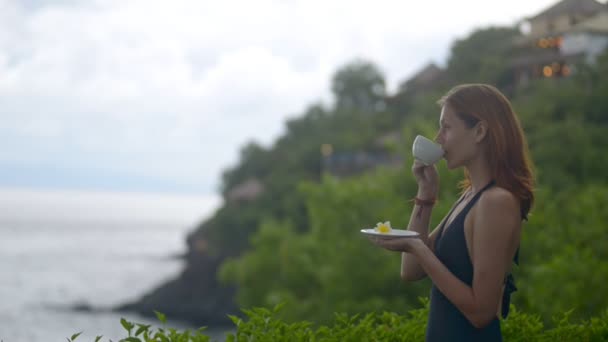 Woman watching the sea on the hill, island and drinking tea. — Stock Video