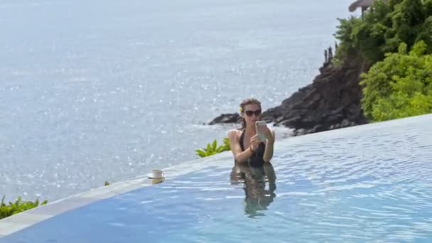 Giovane donna dai capelli rossi americani prendendo selfie in piscina resort di lusso il giorno di sole. — Video Stock