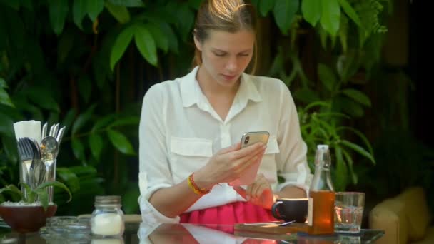 Mujer joven haciendo foto de la comida sentada a la mesa en la cafetería durante el viaje. — Vídeo de stock