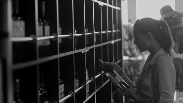 Black and white shot of woman taking a bottle of wine from the counter at the alcohol shop — Stock Video