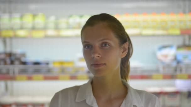 Young woman looking at camera with smile while standing in supermarket during travel. — Stock Video