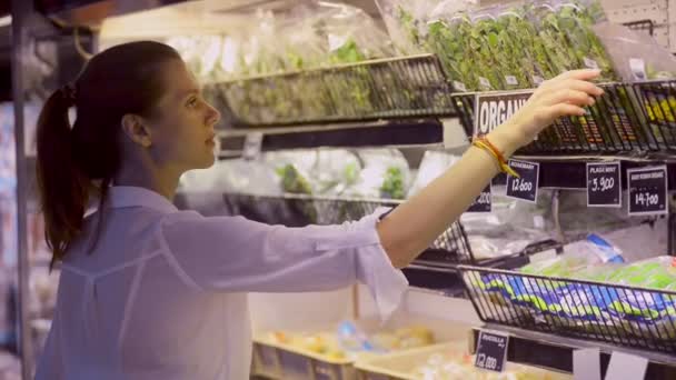 Mutlu genç bayan ev hanımı markette duran yeşil sebzeler alıyor.. — Stok video
