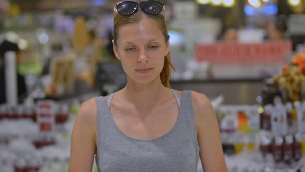 Mooie jonge vrouw kijkt naar camera glimlachend in de supermarkt. portret van een vrouw — Stockvideo