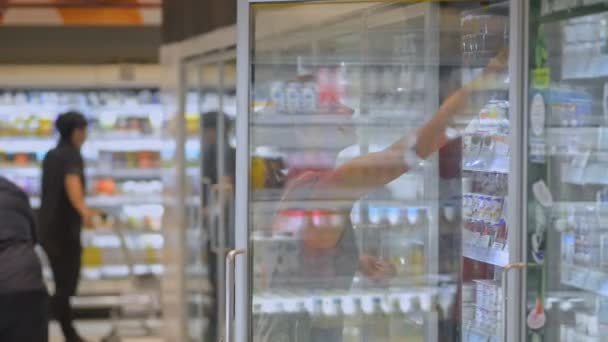 여행하는 젊은 여자가 요구르트 를 사서 아시아 인 여행중에 슈퍼마켓에서 걷는다. — 비디오