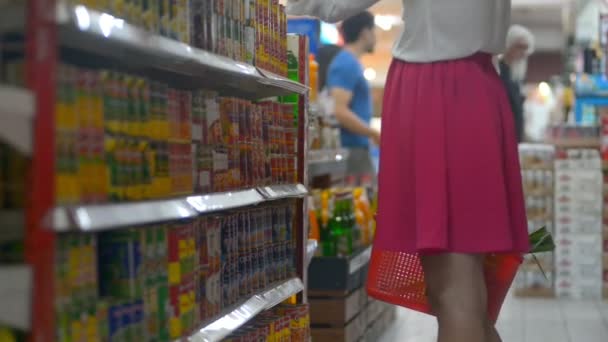 印度尼西亚巴厘- 2019年3月：女性选择罐头食品，并将其放在购物车的篮子里。在商店过道杂货店 — 图库视频影像