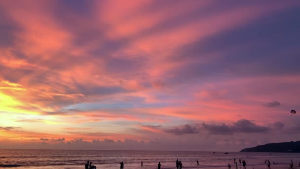 La gente está caminando a lo largo de la playa y el agua durante la puesta de sol en la isla tropical . — Vídeo de stock