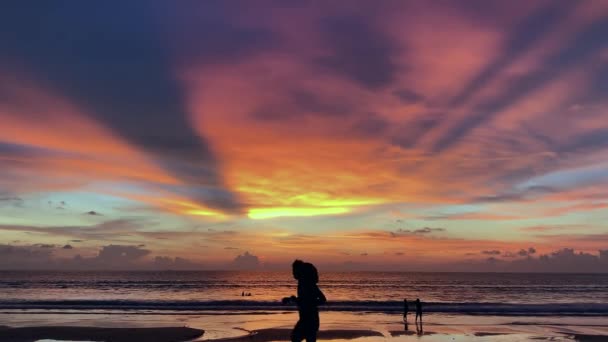 Junges Paar läuft im Morgengrauen am Strand entlang. Menschen und Touristen joggen, gehen schwimmen. Sonnenuntergang — Stockvideo