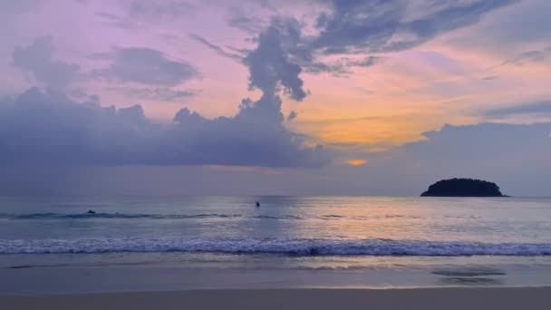 Niebieski zmierzch zachód słońca niebo na plaży z ludźmi pływającymi w morzu i mała sylwetka wyspy. — Wideo stockowe