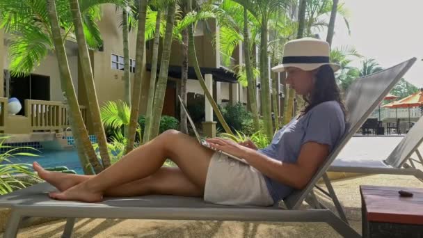 Woman sunbathing with laptop computer in resort with pool. concept distant studying, business — Stock Video
