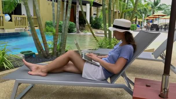 Young woman traveler is using laptop for work during traveling at tropical resort. — Stock Video