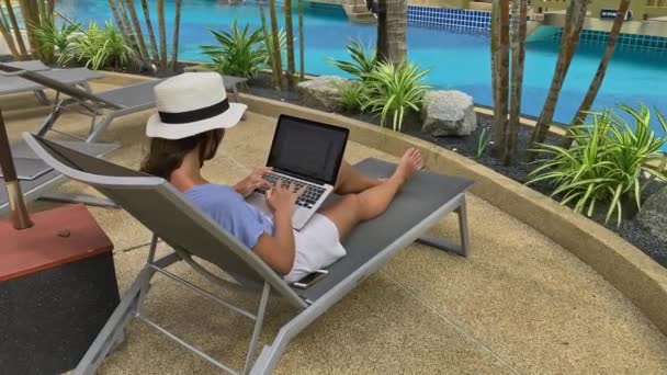 Phuket, Таїланд - січень 2020: жінка-фрилансер, що друкує на ноутбуці біля басейну розкішного курорту. комерсантка — стокове відео