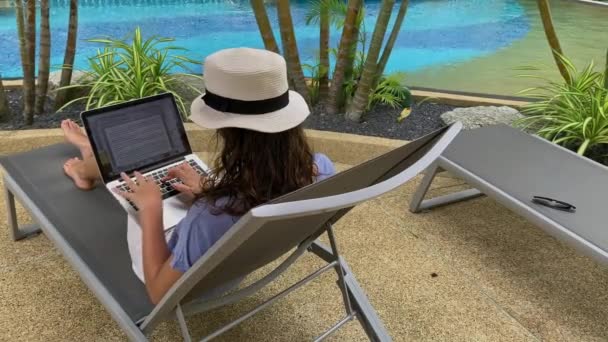 Phuket, Tayland - Ocak 2020: Genç Amerikalı kadın dizüstü bilgisayarla çalışıyor, tatil köyünde güneşlenirken. — Stok video