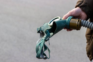 Erkek elinde yeşil gaz maskesi. Endüstriyel, biyolojik ve radyoaktif kirlilik veya virüs koruması sırasındaki kişisel koruyucu ekipmanlarla ilgili konsept posterleri için kopya alanı olan arkaplan