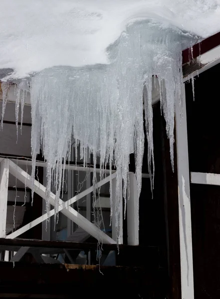 家の屋根からぶら下がって危険な大きな氷のつらら — ストック写真