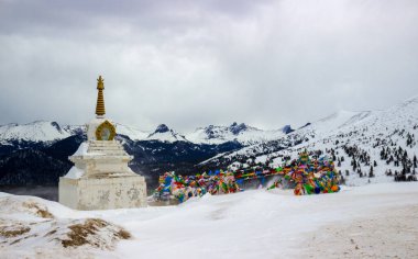 Rusya 'nın güney Sibirya' daki Batı Sayan Dağları 'ndaki Ergaki sıradağlarında kışın renkli dua bayrakları sallayan Budist stupası.