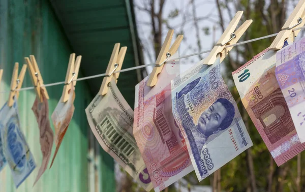 Foreign currency banknotes hanging on wooden clothespins on a rope. Laundering money. Selective focus