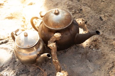 Geleneksel Berber çayı pişirme. Sahra Çölü 'nde şenlik ateşinde siyah, ıslak çaydanlıklar. Isıtıcıda güneş parlıyor