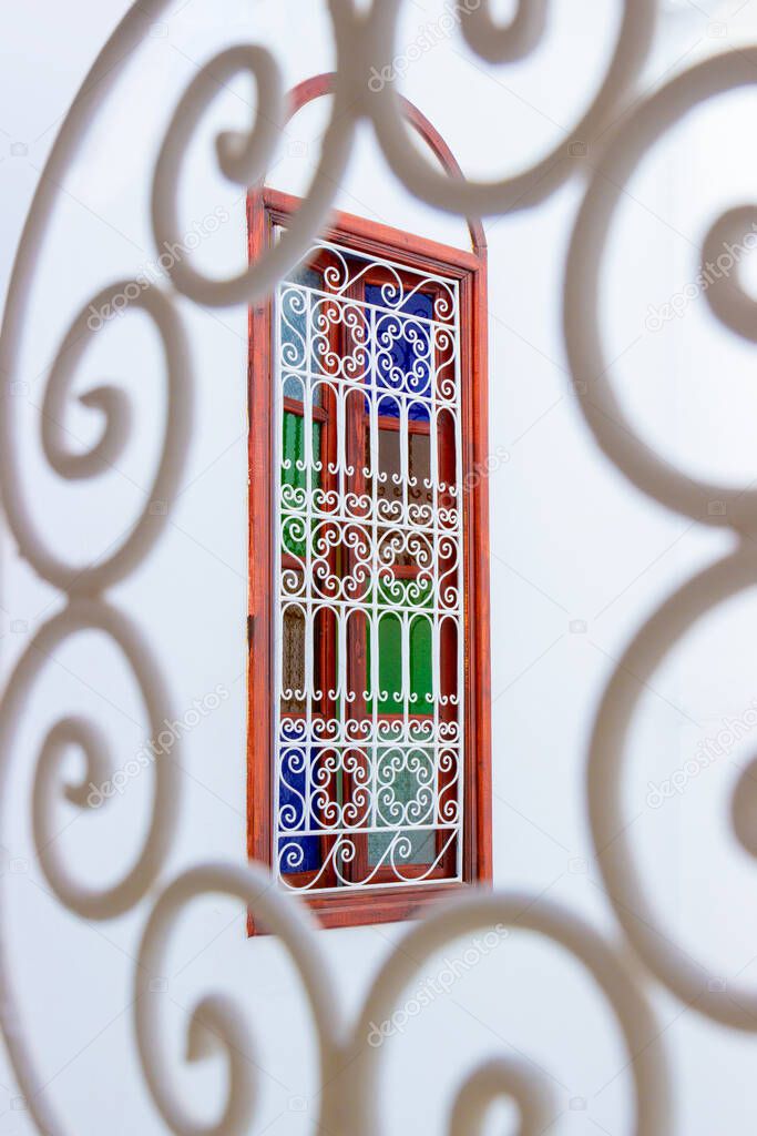 Window with multi-colored glass and arabic lattice in Marrakesh, Morocco. Moroccan authentic interior in medina quarter. Colorful oriental stained glass. Selective focus