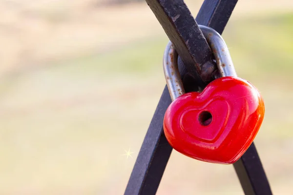 Promise of eternal love. Red heart shaped love padlock. Wedding tradition of the newlyweds. Symbol of fidelity. Copy space, blurred background