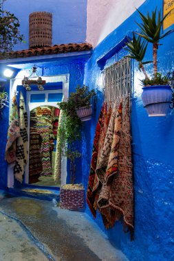 Chefchaouen, Fas - 20 Ekim 2019: Chefchaouen, Fas 'taki hediyelik eşya dükkanında el yapımı Fas halıları. Renkli Fas etnik hatıraları. Medine 'de bir sokak..