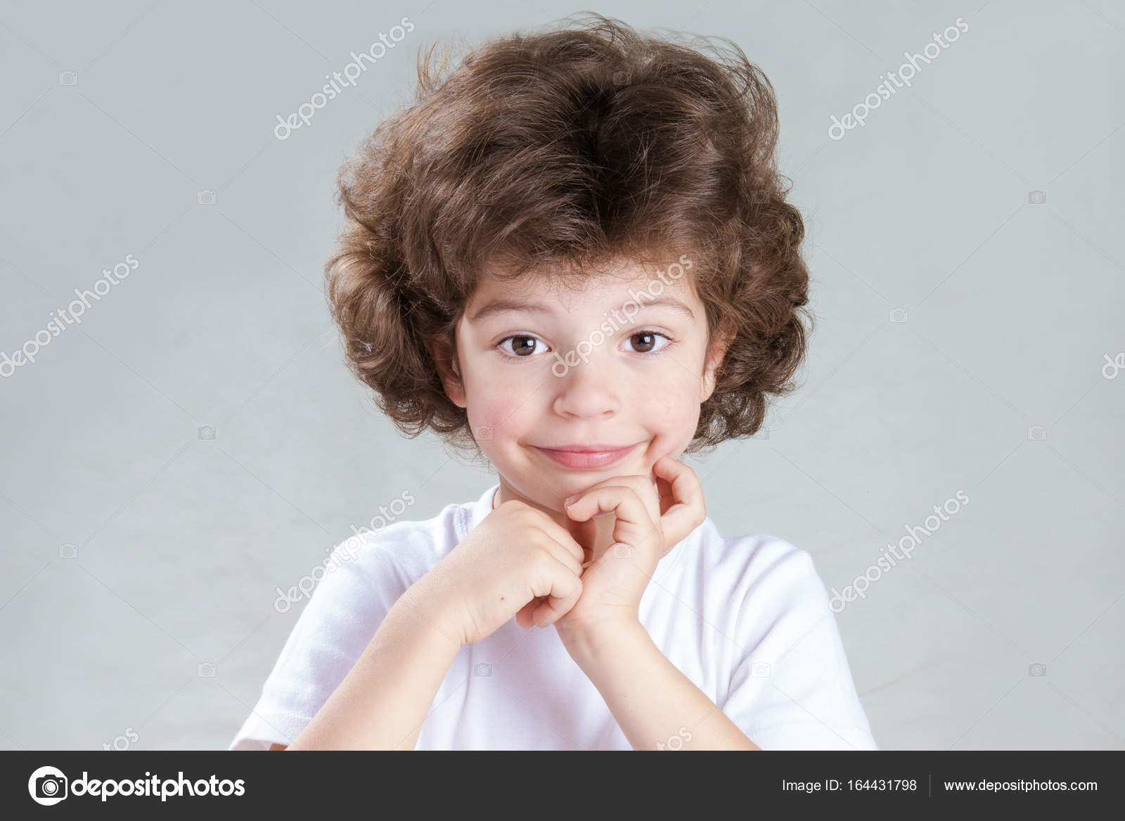 Charming Little Curly Haired Boy In A White Shirt Looks Into The