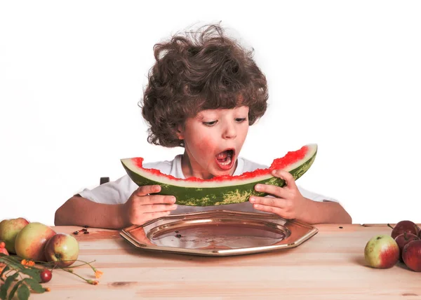 Little curly boy eats large ripe watermelon. White background. Close-up. — Stock Photo, Image