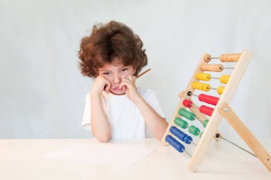 Saymak öğrenme şirin bebek çocuk ağlıyor. Masaya oturur. Kameraya bakıyor. Gri arka planı.