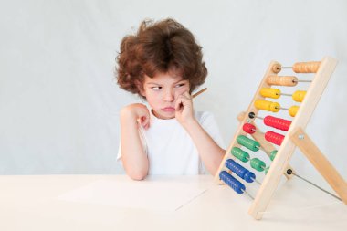 Sevimli çocuk kısma gözleri sonuçlarına bakarak ağlayan. Masaya oturur. Gri arka planı.